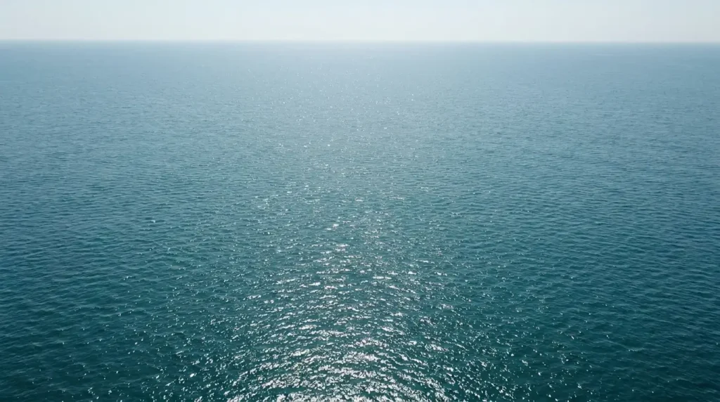 Aerial view of open ocean surface with natural sunlight on a calm clear day representing the modern seawater source from which sea salt is produced